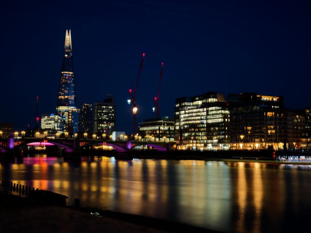 Stunning night view of London's skyline featuring The Shard and city lights reflected in the Thames.