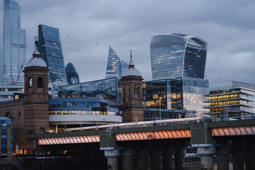 Glowing bridge with towers crossing river near contemporary futuristic multistory office buildings located on street of Londo