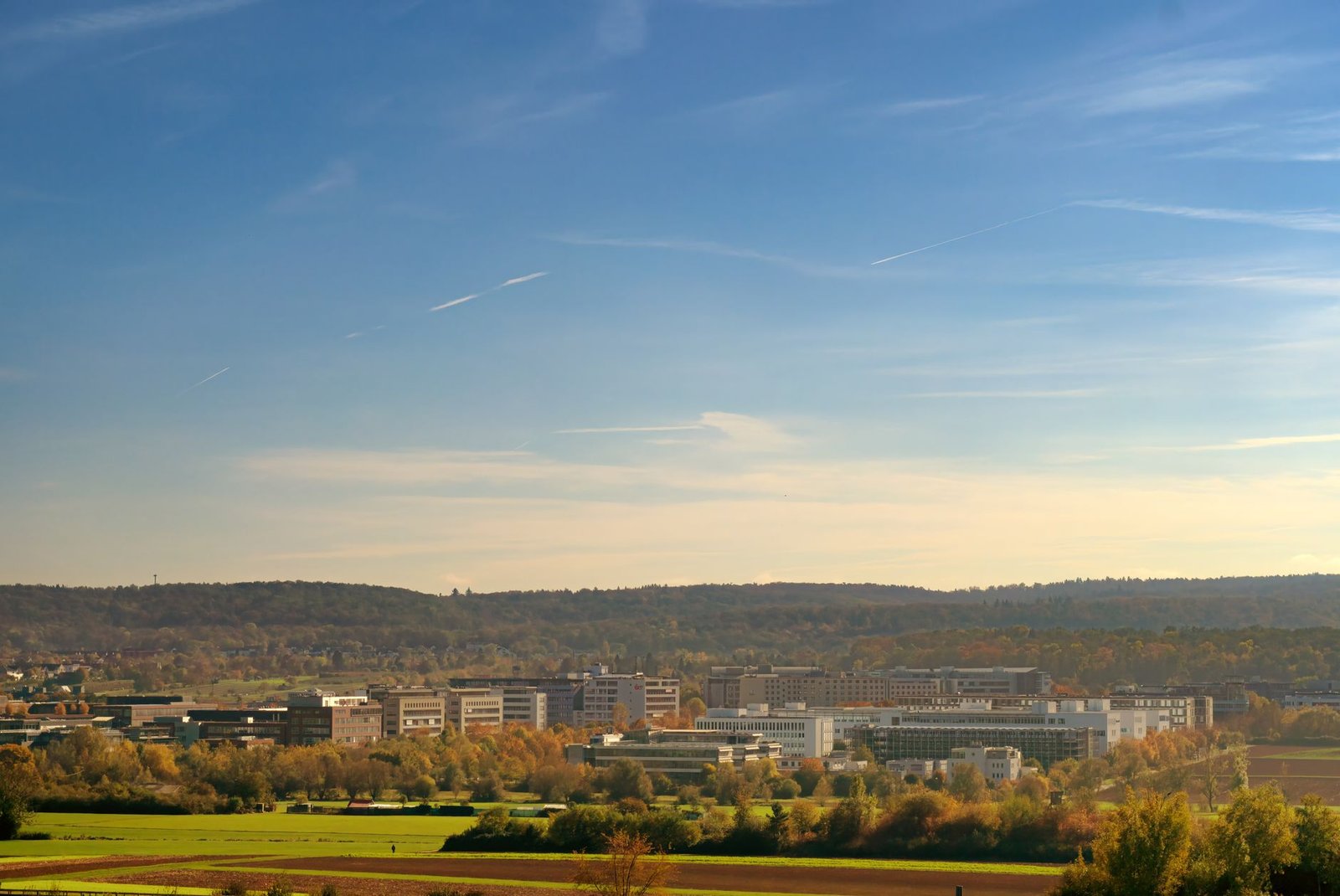 A panoramic view of Stuttgart's industrial district with buildings and greenery under a clear blue sky.