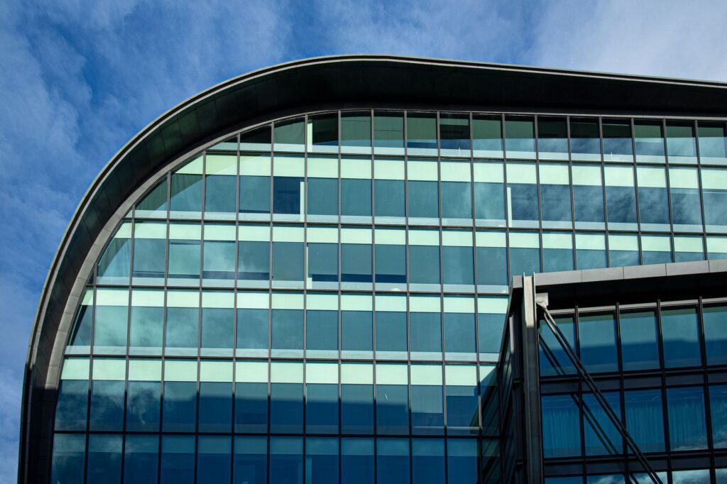 Futuristic glass facade of a modern building in London with a clear blue sky.