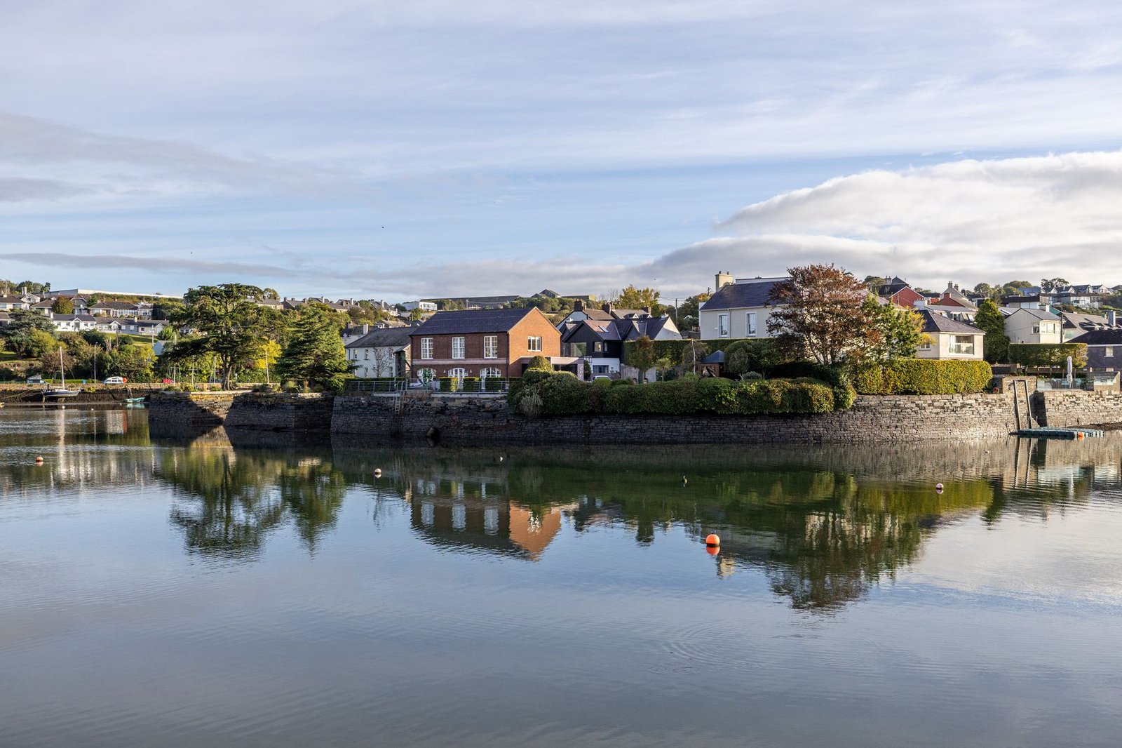 Charming waterfront houses reflected on calm water in Kinsale, County Cork, Ireland.