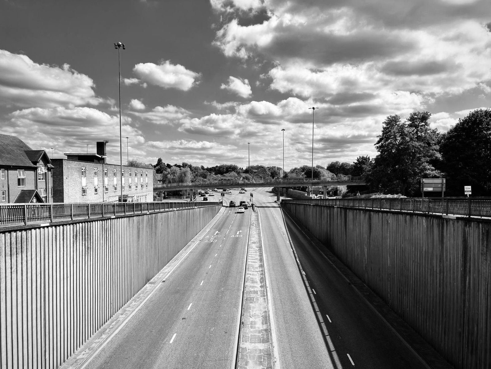 A black and white photograph of a motorway in Reading, England under a bright sky.