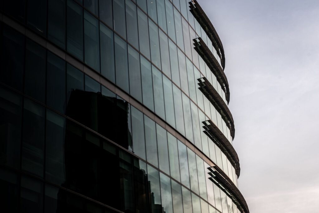 Contemporary glass office building reflecting cityscape in London, UK.