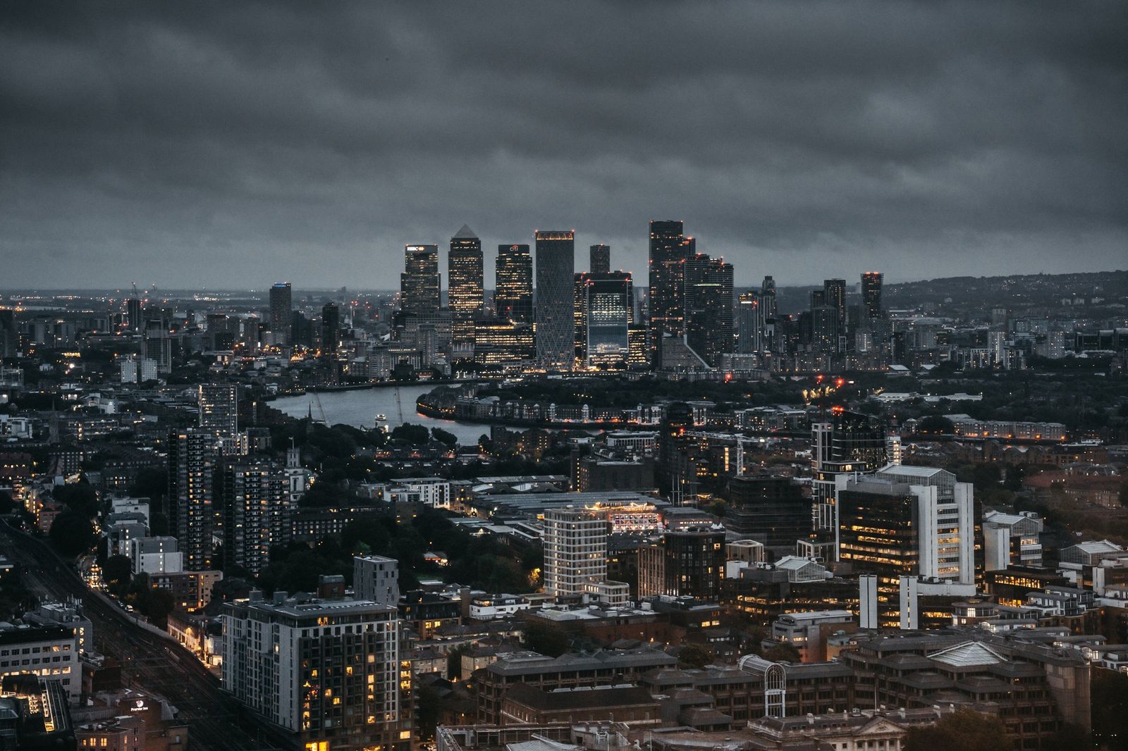 Stunning aerial view of a city's illuminated skyline at night, showcasing skyscrapers and a winding river.