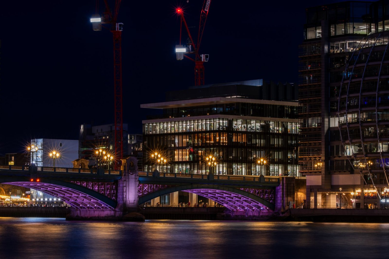 Captivating view of illuminated modern buildings and bridge along the River Thames in London at night.