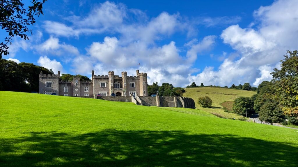 Picturesque Watermouth Castle surrounded by lush green countryside under a clear blue sky in Devon, England.