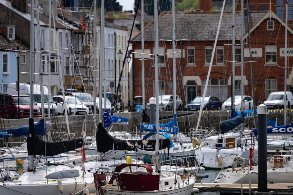 Scenic view of boats docked at Weymouth Harbour, England, with historic brick buildings in the background.