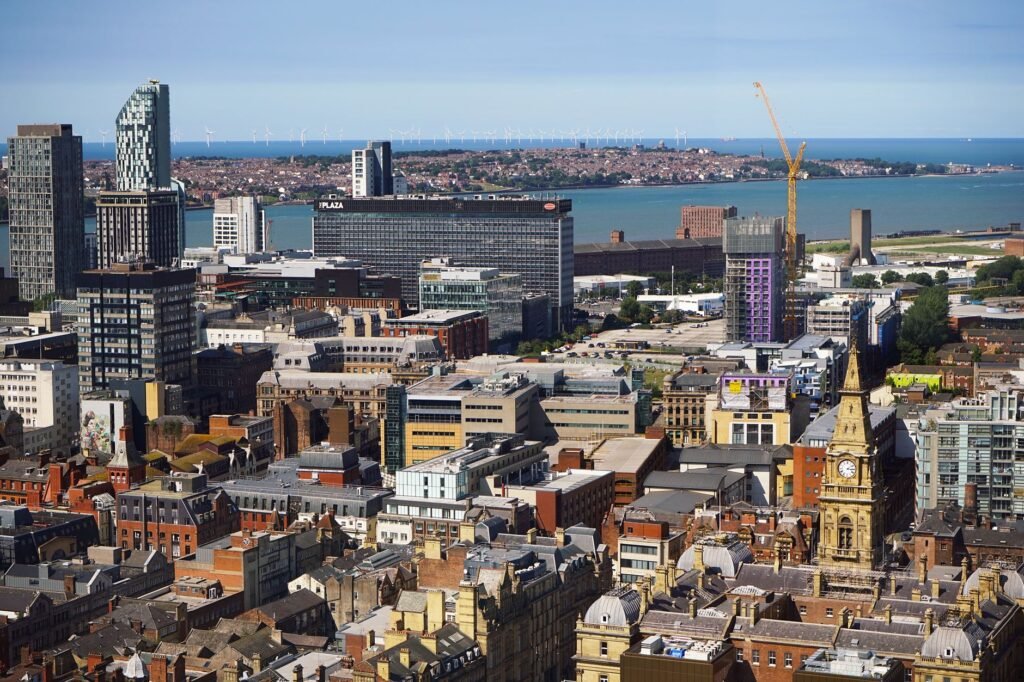 Aerial view of Liverpool showcasing modern skyscrapers and historic architecture by the harbor.