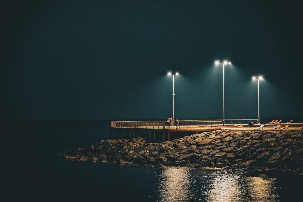Tranquil pier scene at night in Trabzon, Türkiye, with streetlights and waterfront reflections.