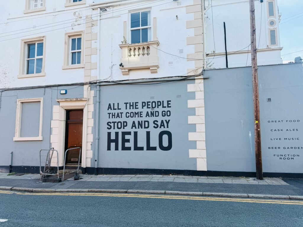 Urban scene featuring a vibrant street mural with a welcoming quote on a building wall.