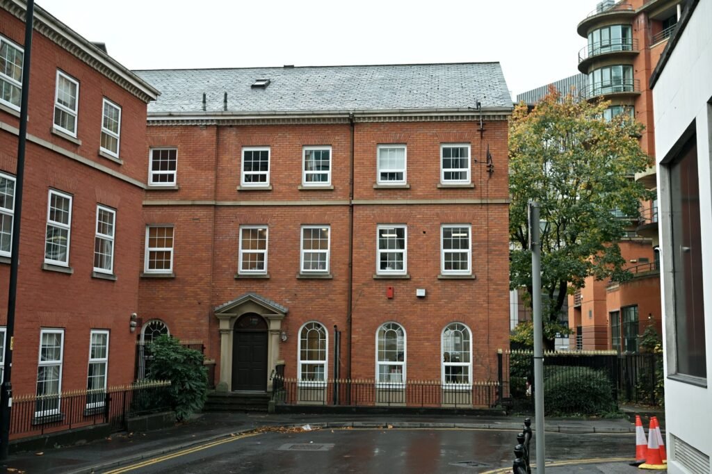 A traditional red brick building in a modern cityscape, showcasing architectural blend.