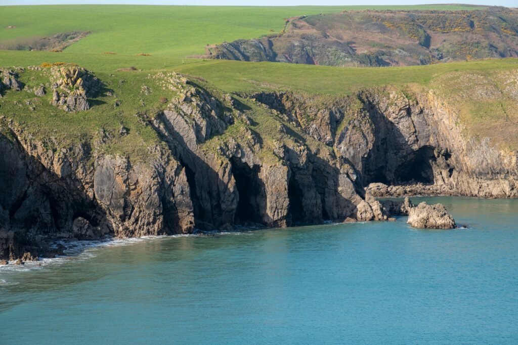 A breathtaking view of rugged cliffs and turquoise waters along the Welsh coastline, perfect for nature enthusiasts.