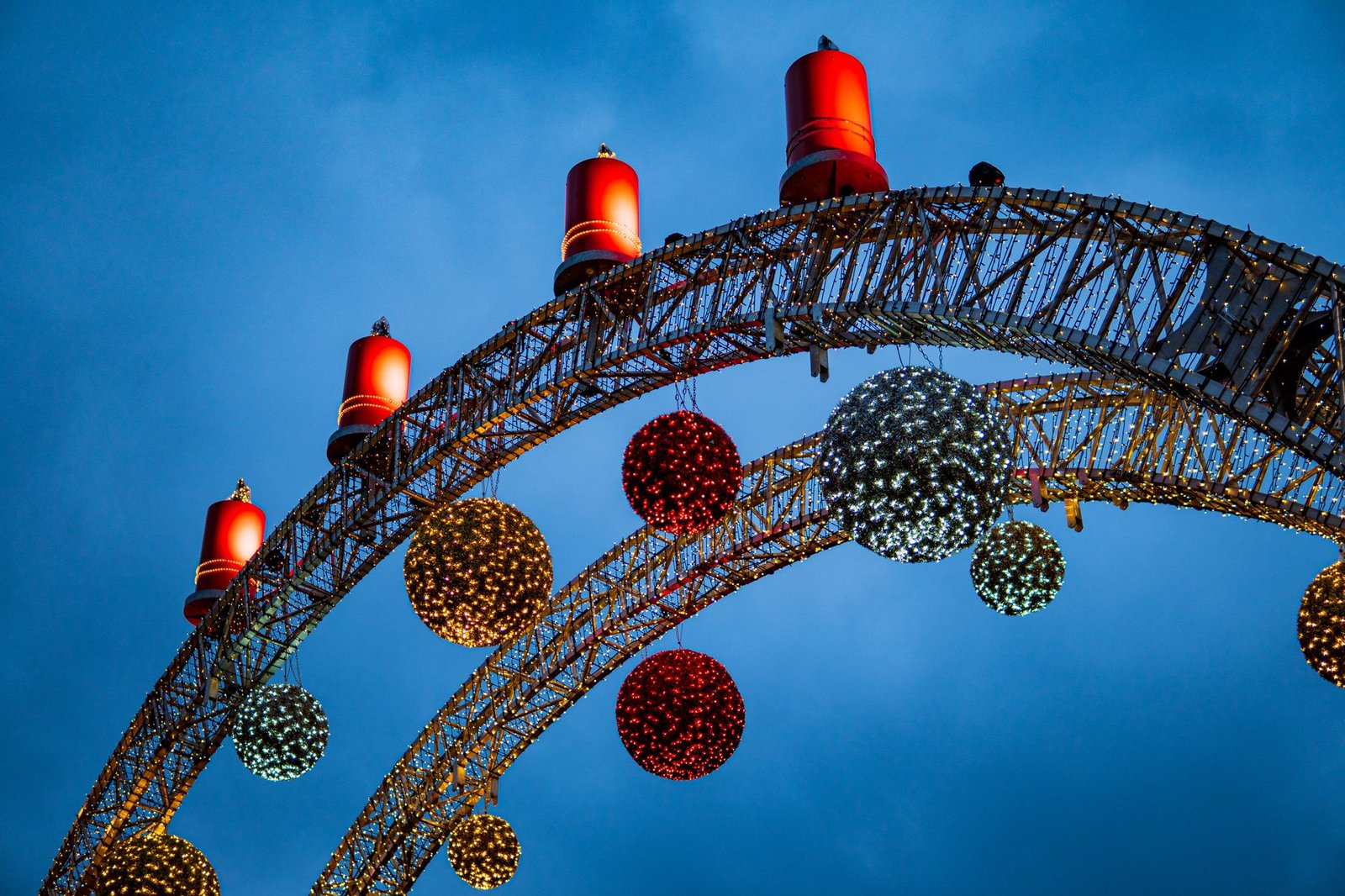Festive Christmas decorations with lights and arches against a blue sky in Vienna at night.
