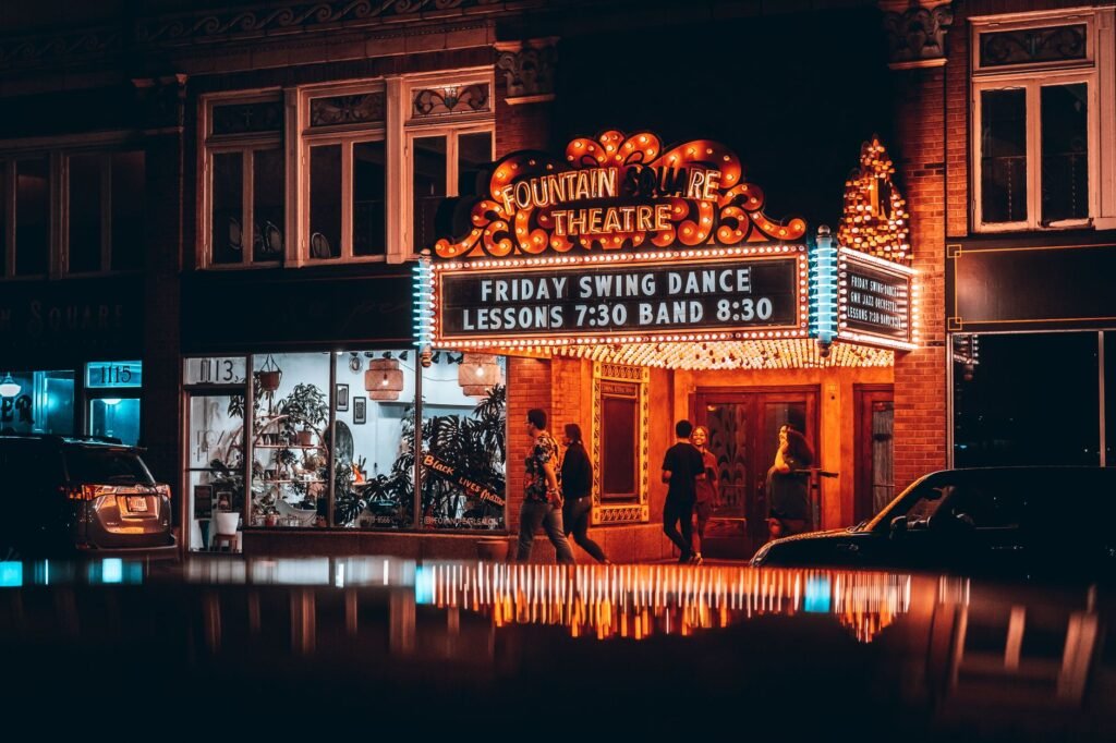 Vibrant night scene of Fountain Square Theatre in Indianapolis with neon lights and reflections.