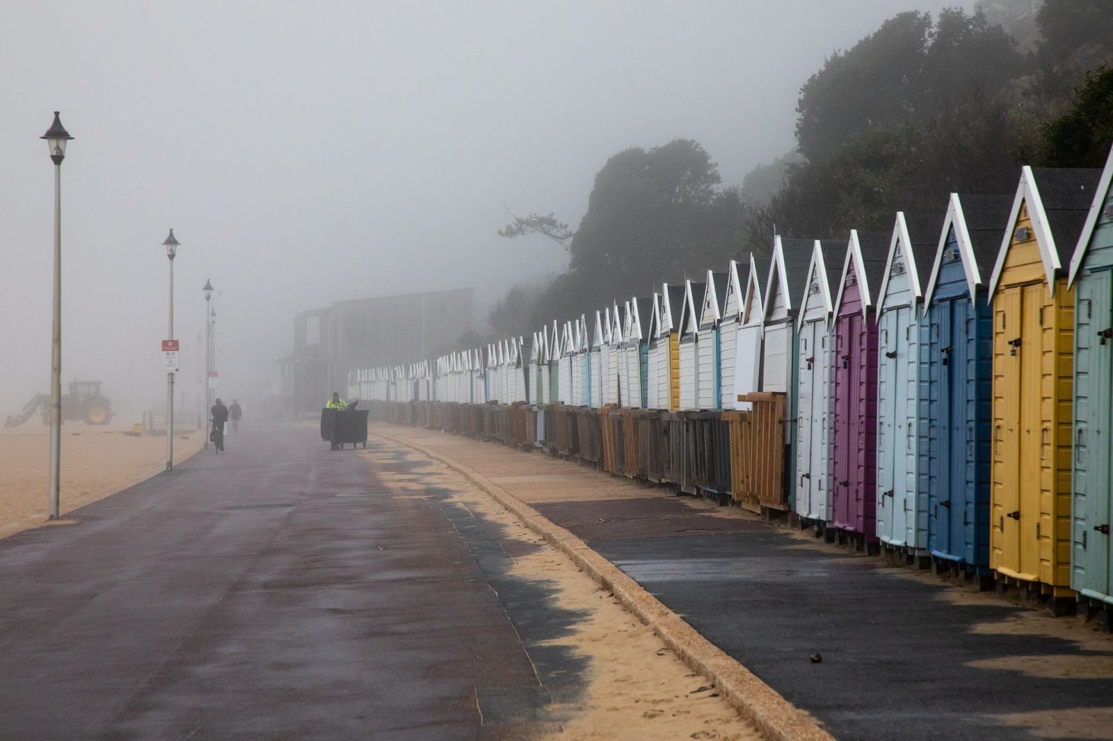 Colorful beach huts line Bournemouth Beach on a foggy morning.