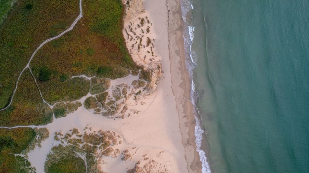 Stunning aerial view of a Cornwall beach with intricate sand patterns and waves at dawn.