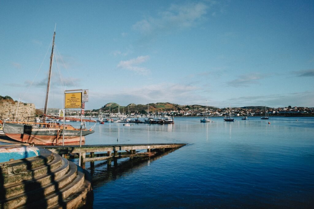Picturesque view of Conwy Harbor, Wales, with boats and vibrant waters on a clear day.