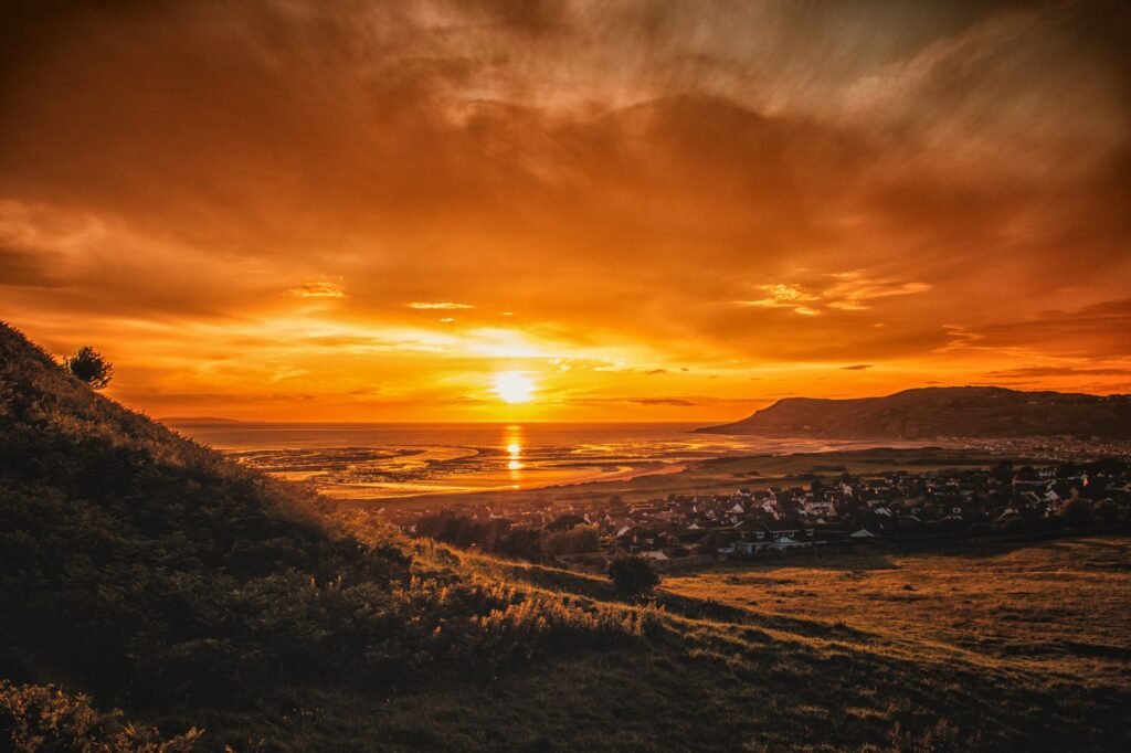 Stunning sunset over a coastal village with vibrant skies and lush greenery.