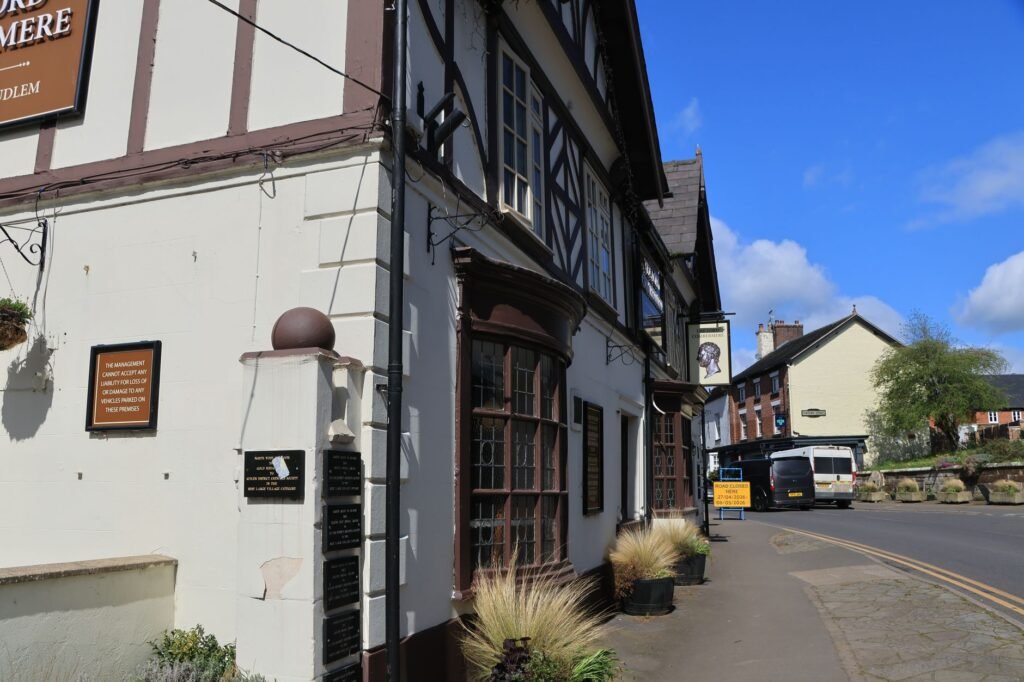 Traditional English village street with historic Tudor-style building and clear skies.