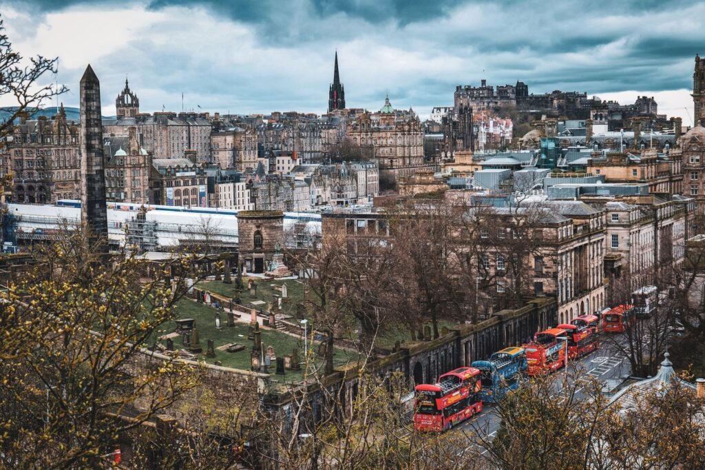 Aerial view of Edinburgh city with iconic landmarks and classic red buses.