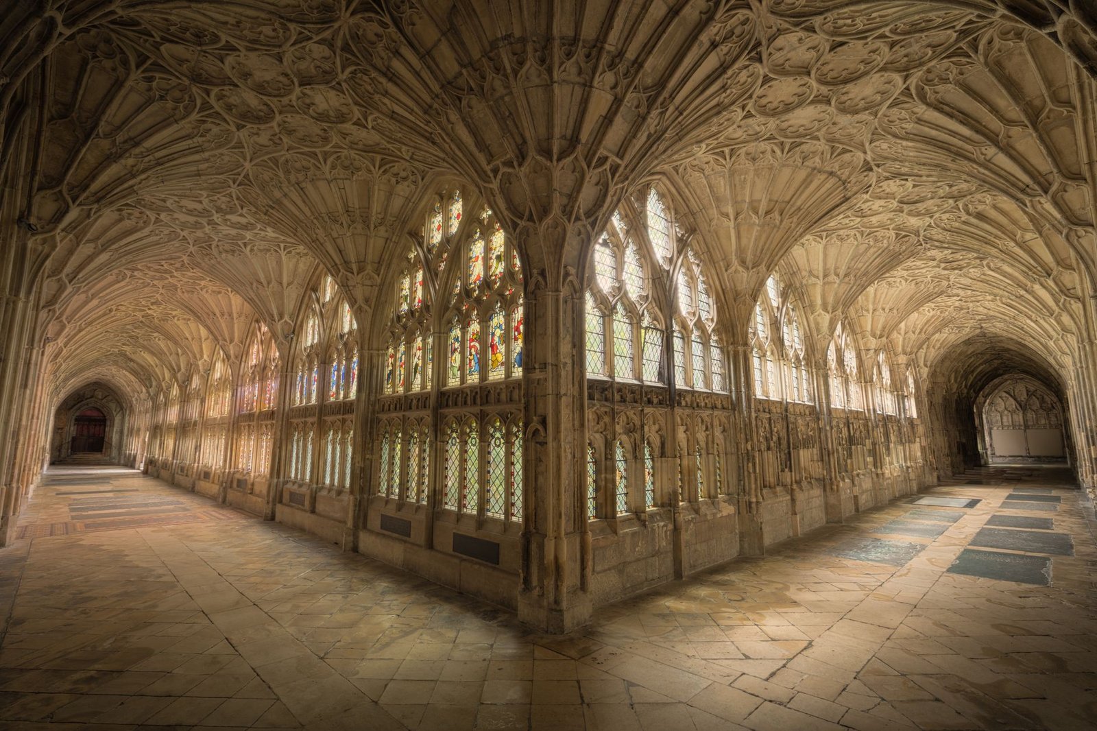 Intricate gothic cloisters with stained glass windows in Gloucester Cathedral, England.