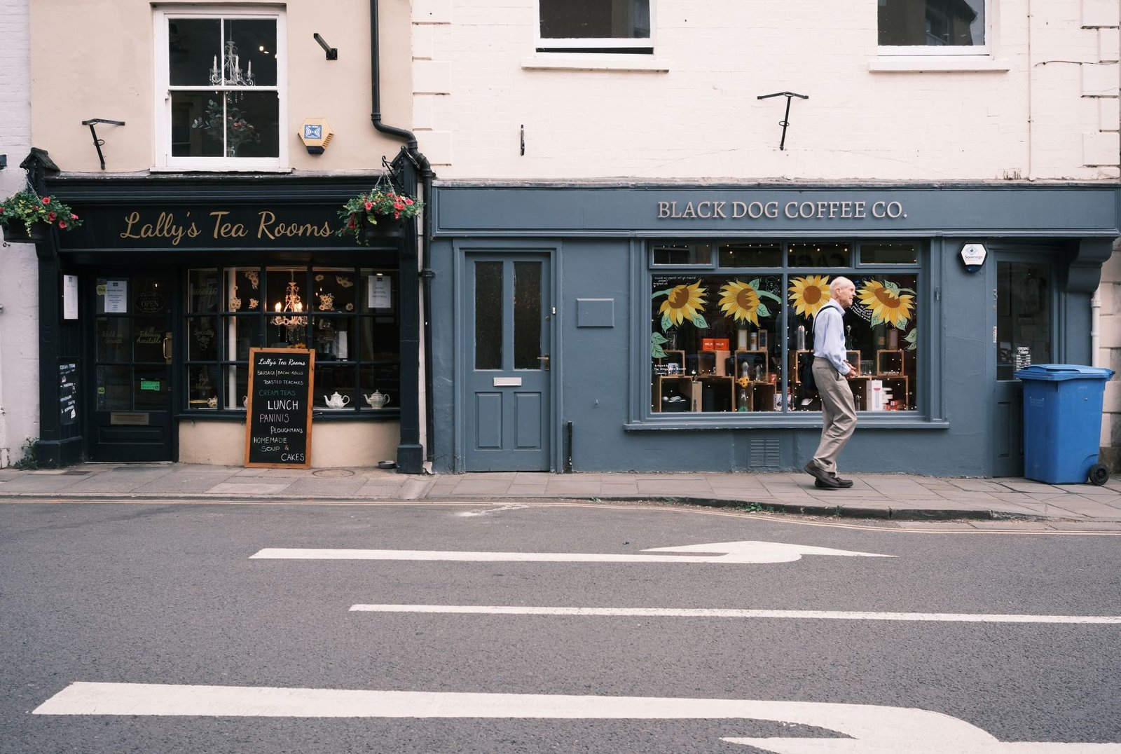 A quaint street view showing a tea room and coffee shop with a passerby.