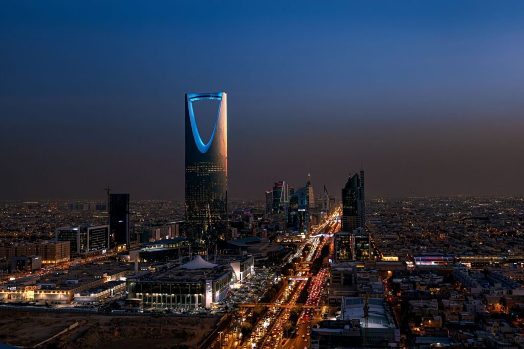 A breathtaking aerial view of Riyadh at night featuring the iconic Kingdom Centre Tower.