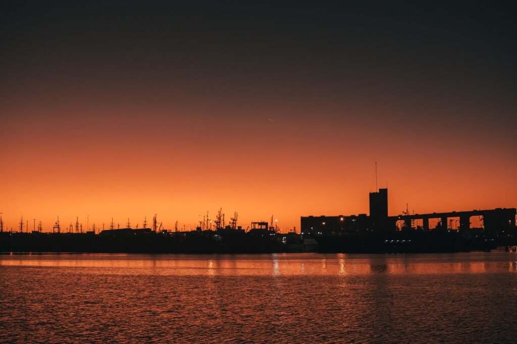 Beautiful silhouette of a city harbor against a vibrant sunset sky reflecting on the water.