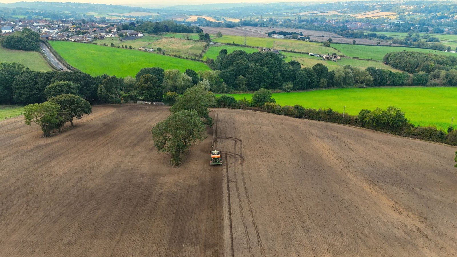 Aerial view of a tractor preparing fields near Wakefield, surrounded by lush greenery.