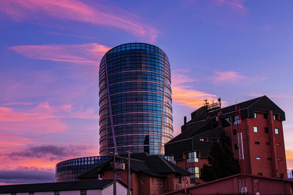 Modern glass skyscraper with vibrant sunset sky, creating a striking urban skyline.