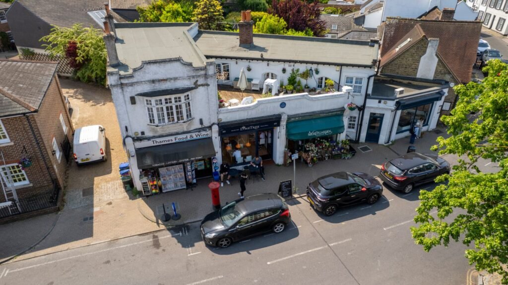 Aerial view of shops and cars on a sunny street in Thames Ditton, UK.