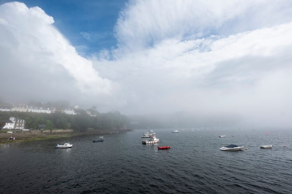 Misty seascape of Portree harbour with boats, showcasing the natural beauty of Scottish landscape.