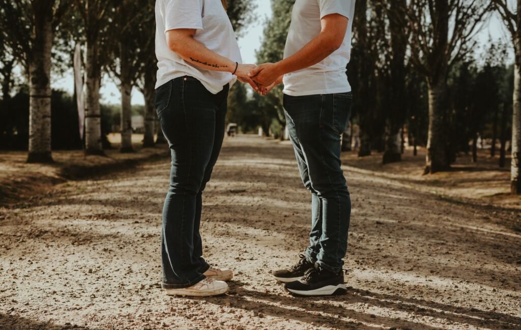 A couple holding hands on a tree-lined path, symbolizing love and connection.