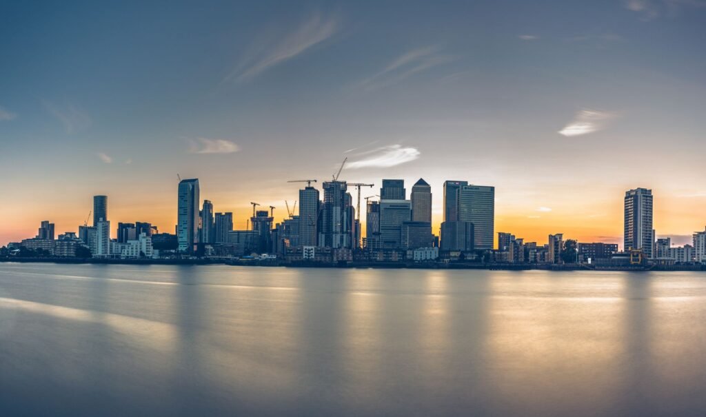 Stunning sunset view of Canary Wharf skyline reflecting in the Thames water.