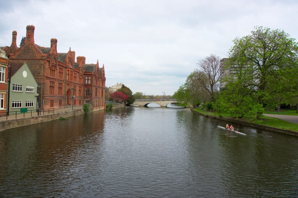 Rowers on the River Great Ouse with historic brick buildings and a bridge in Bedford, England.