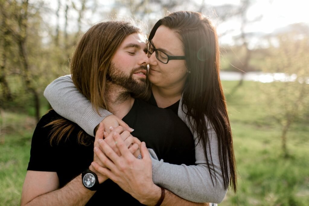 A couple lovingly embracing outdoors during a sunny day in the park.