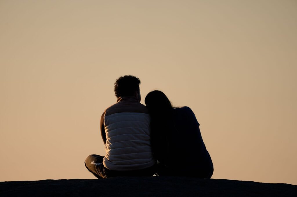 A couple sitting and embracing while watching the sunrise at a park, symbolizing romance and peace.