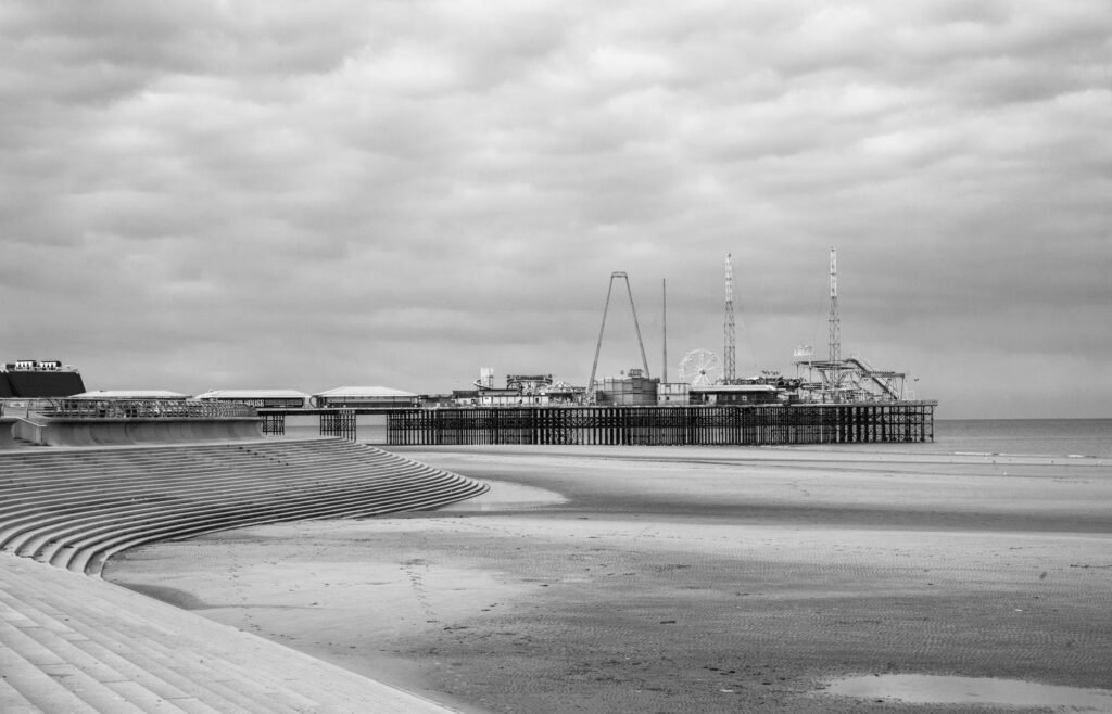 Blackpool Pier in England with overcast sky, capturing the seaside architecture in black and white.