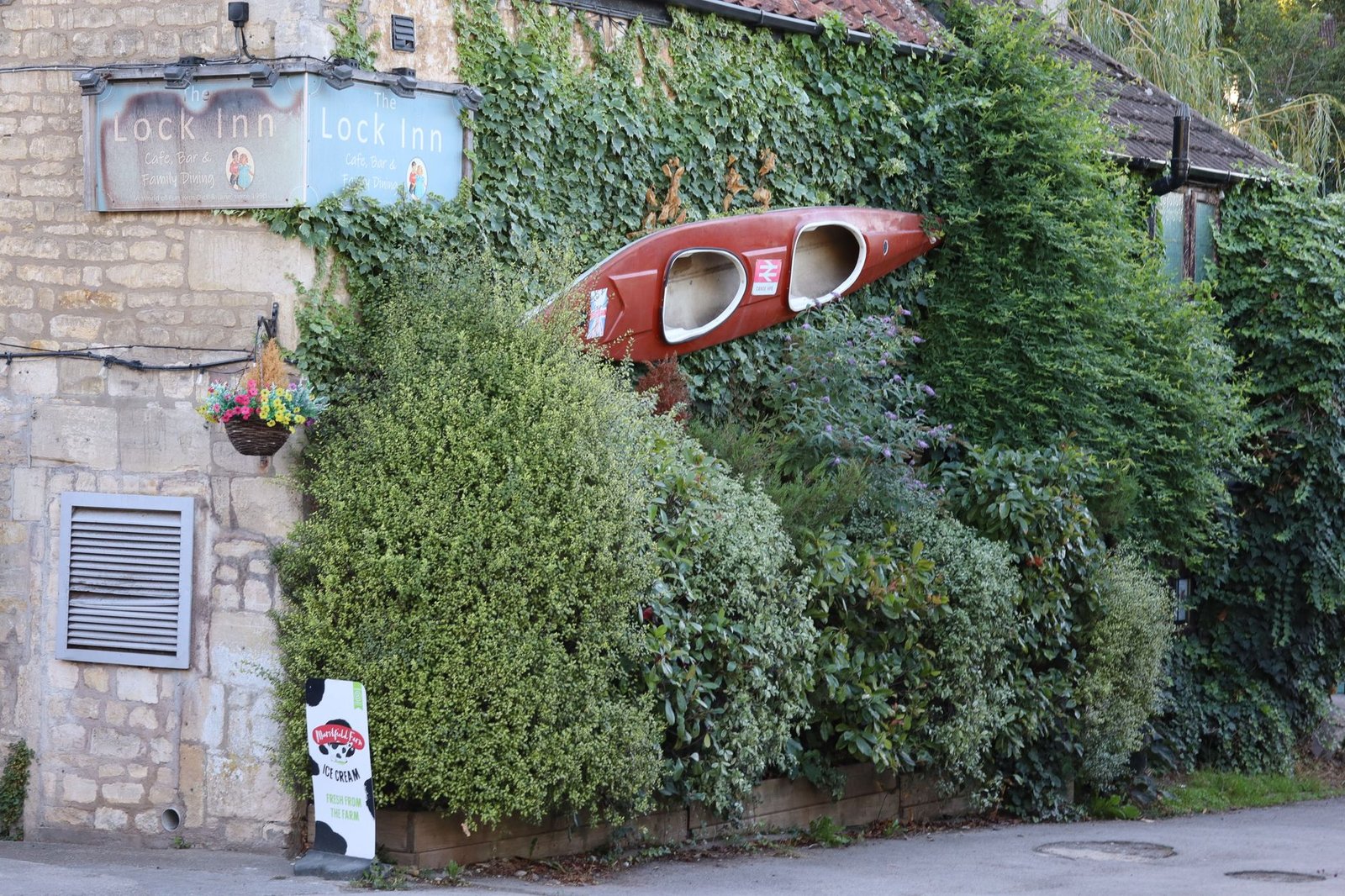 Charming Lock Inn pub with a vintage canoe framed by lush greenery in the UK. Perfect blend of nature and architecture.