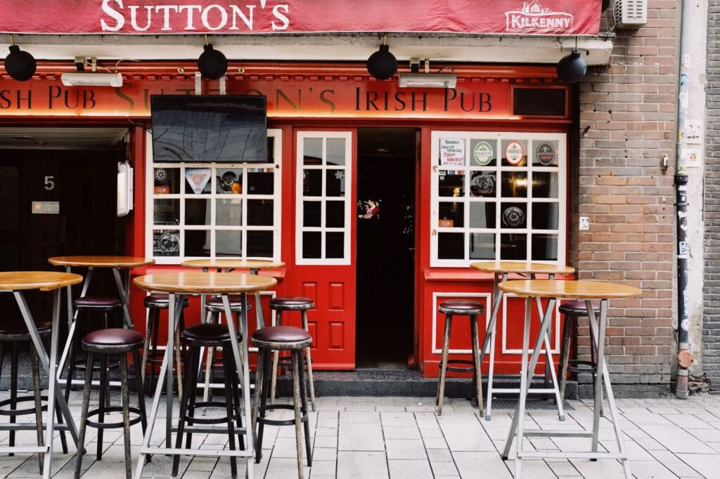 Outdoor seating area of Sutton's Irish Pub with inviting red facade and empty tables.