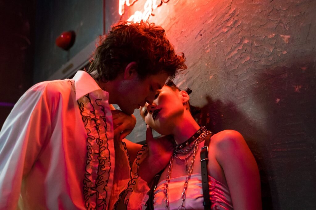 A couple sharing a tender moment under vibrant neon lighting in an urban setting.