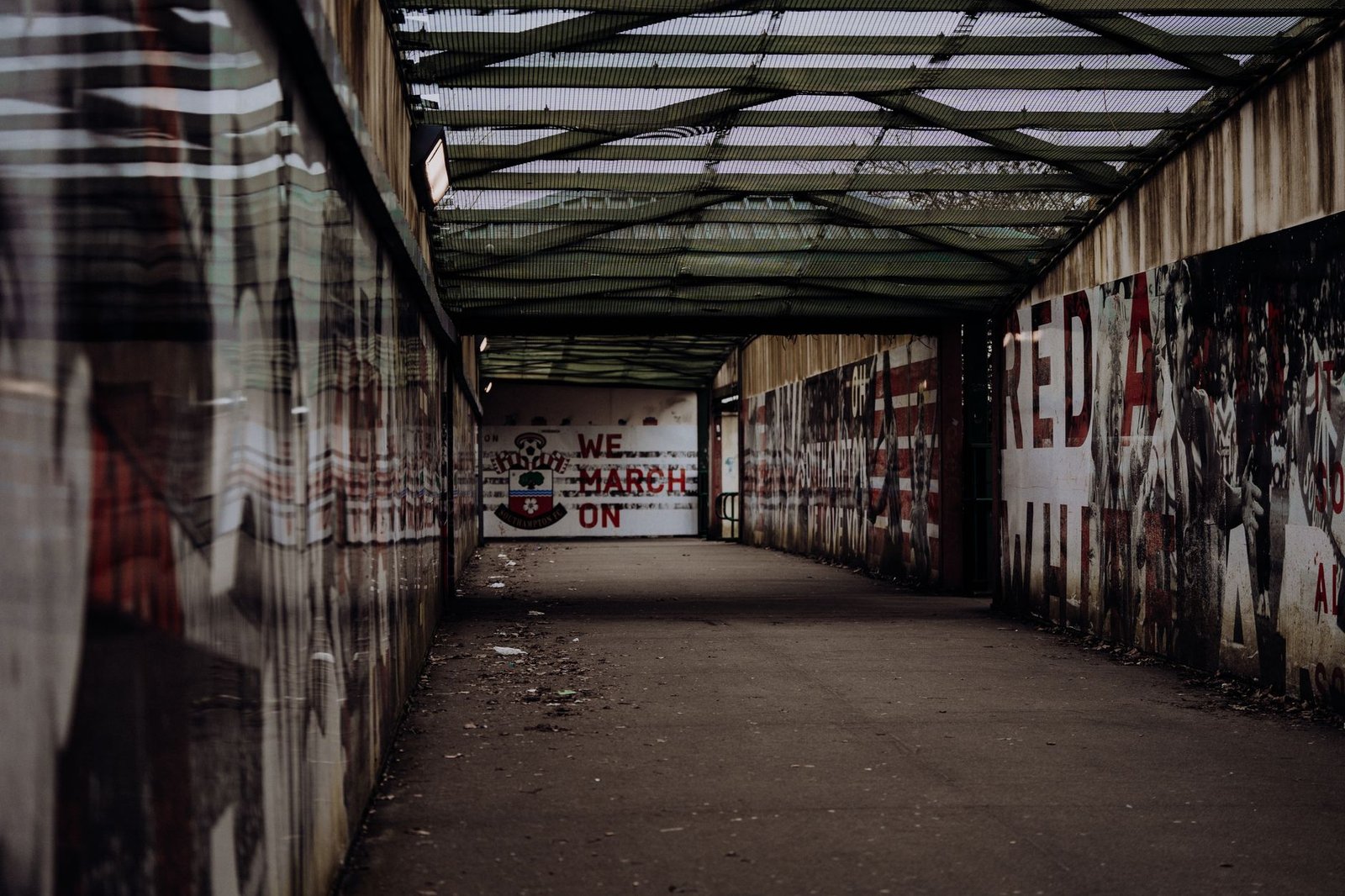 An urban walkway featuring football-themed graffiti at St Mary's Stadium in Southampton, England.