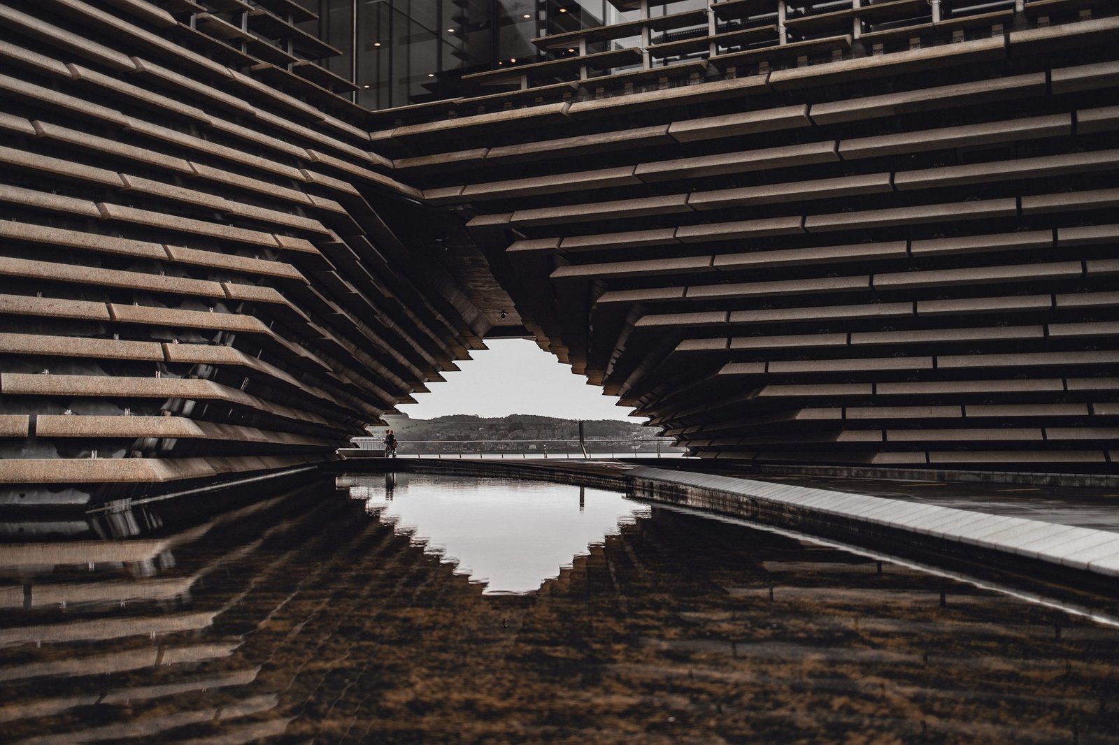 Intricate modern design of the V&A Dundee with reflections in a pond, Scotland.
