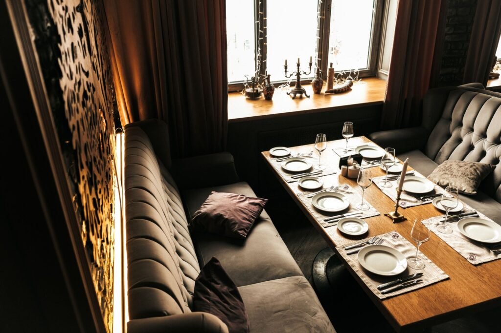 Elegant restaurant setup with luxurious sofas and prepared table for dining.