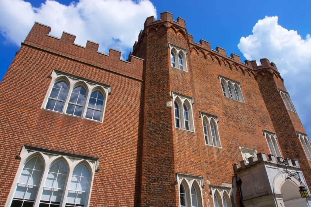 Low angle view of a historic brick castle in Hertford, England, showcasing its gothic architecture.