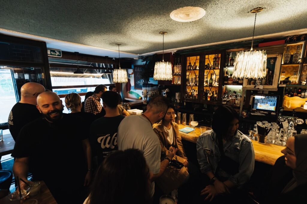 Cozy bar setting with people enjoying drinks and conversation under warm lighting.
