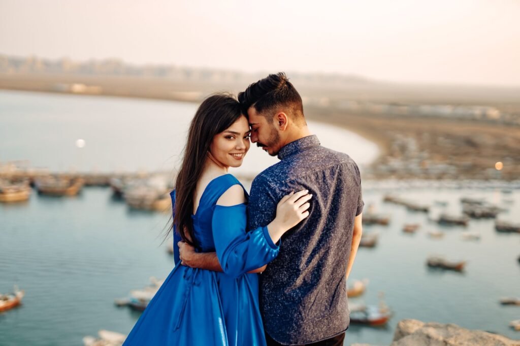 A couple embraces near the sea during sunset, exuding romance and serenity.