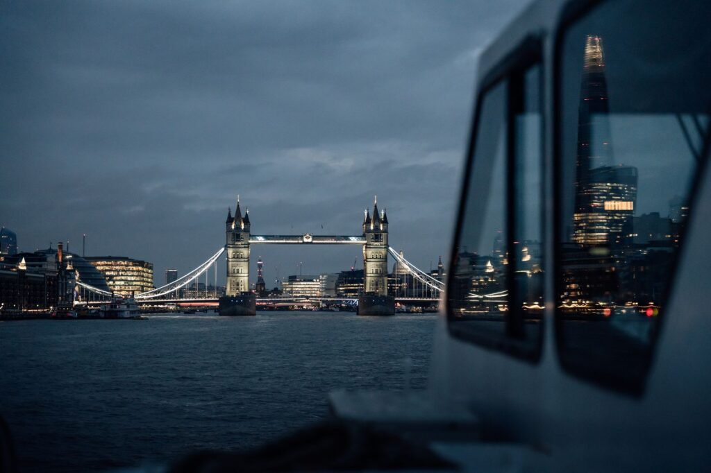 Scenic nighttime view of London's Tower Bridge and The Shard, reflecting city lights over River Thames.