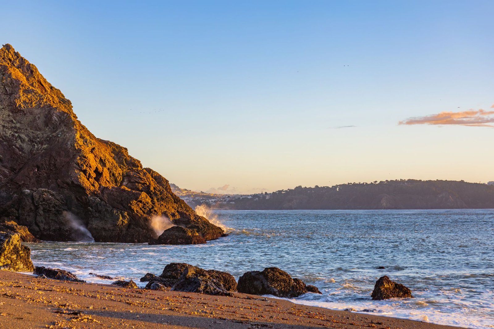 Scenic view of a rocky coastline with waves crashing during sunset.