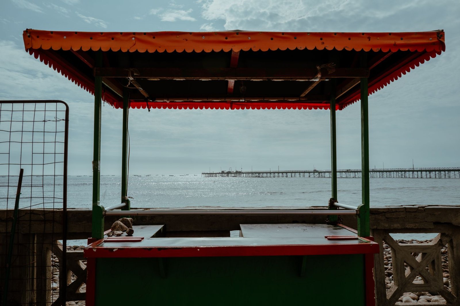 A vibrant, empty kiosk by the ocean with a view of Pacasmayo Pier in Peru, captured on a bright day.